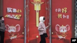 北京居民走過仍然懸掛著春節招貼畫的商場旁走過。（2020年3月8日）