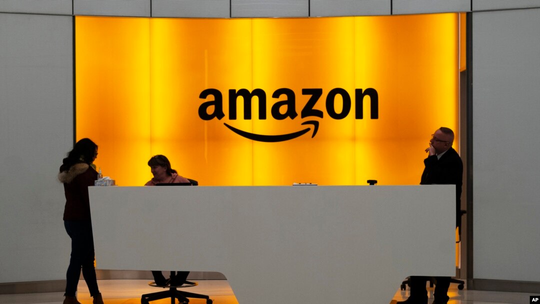 FILE - In this Feb. 14, 2019, file photo people stand in the lobby for Amazon offices in New York.