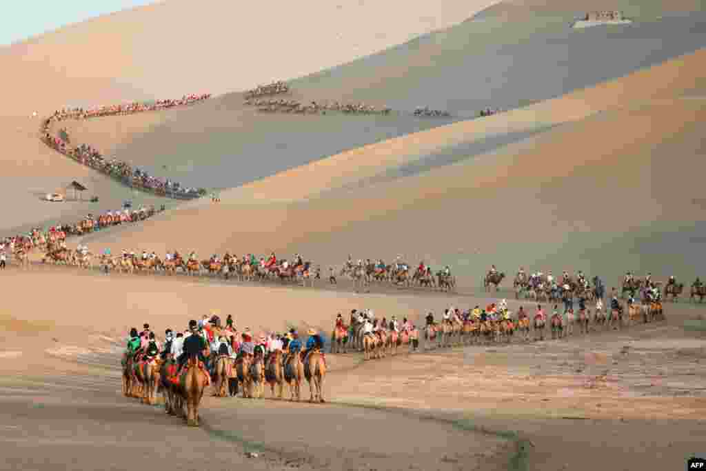 Tourists ride camels in the desert in Dunhuang in China's northwestern Gansu province.