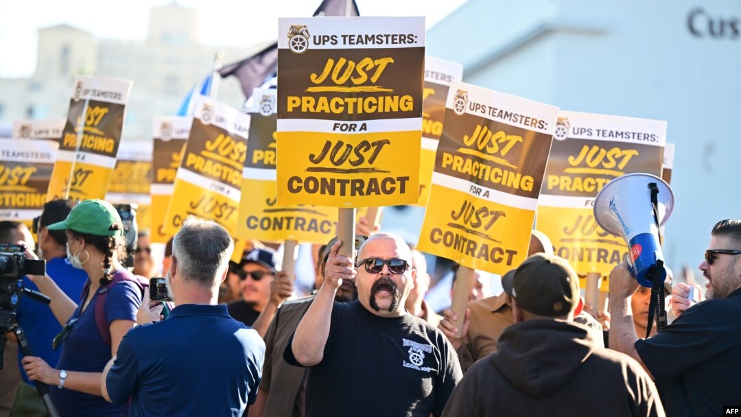 FILE - UPS workers hold placards at a rally held by the Teamsters Union on July 19, 2023 in Los Angeles, California, ahead of an August 1st deadline for an agreement on a labor contract deal. (Photo by Frederic J. BROWN / AFP)
