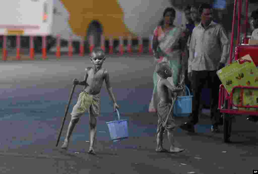 Young boys with their bodies painted and dressed as Mahatma Gandhi seek alms at a traffic intersection in Hyderabad, India.