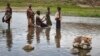 FILE - A Turkana woman and children bathe in a hot spring pool in northwestern Kenya inside the Turkana region of the Ilemy Triangle, Sept. 26, 2014.