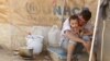 A Syrian refugee holds his child as he sits by his tent at Al Zaatri refugee camp in the Jordanian city of Mafraq, near the border with Syria, September 9, 2012. 