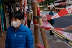 A woman wearing face mask walks on a street in Hong Kong, Feb. 18, 2020. COVID-19 viral illness has sickened millions of people in China since December.