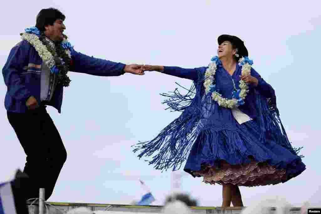Bolivia's President and current presidential candidate for the Movement for Socialism (MAS) party Evo Morales, left, dances during a closing campaign rally in El Alto, Oct. 16, 2019.