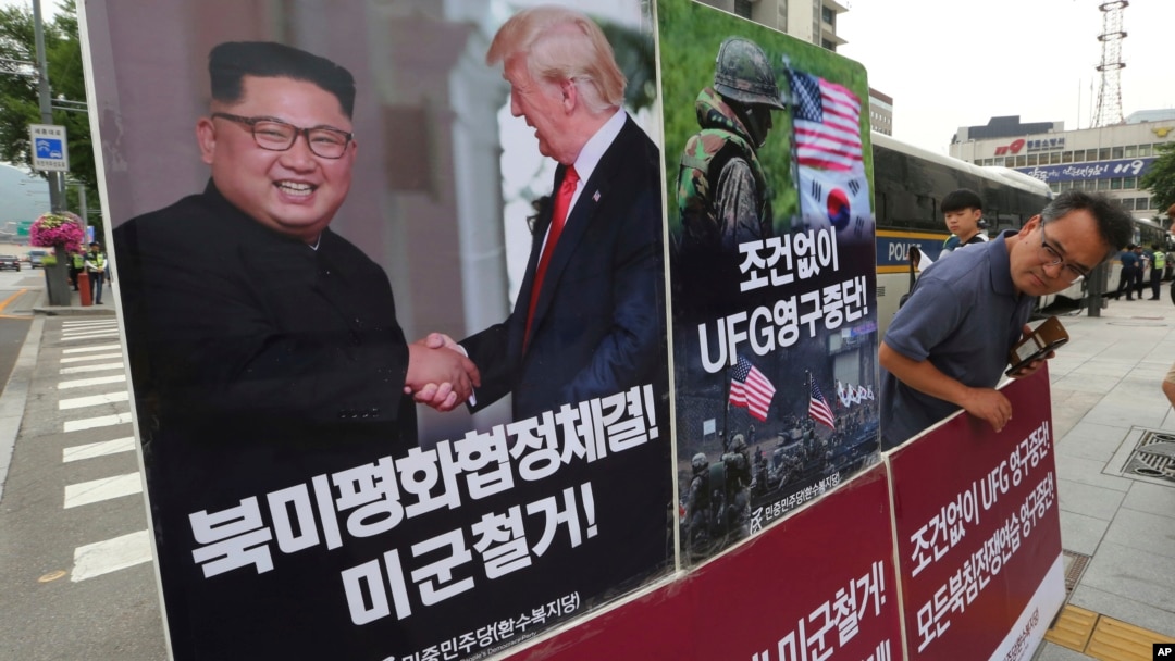 FILE - A photo showing U.S. President Donald Trump and North Korean leader Kim Jong Un is displayed as a member of People's Democratic Party stands to oppose military exercises between the United States and South Korea, near the U.S. Embassy in Seoul, South Korea.