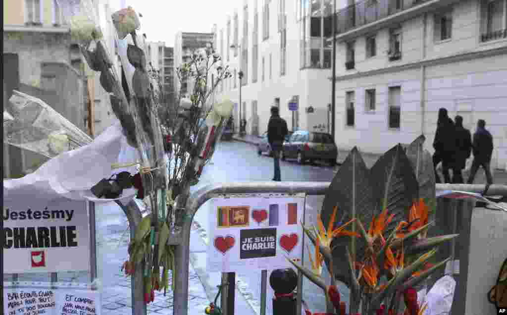 Flowers are attached to security fences outside Charlie Hebdo headquarters one week after the attack on the newspaper, in Paris, France, Jan. 14, 2015.