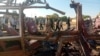 FILE - People walk past a destroyed vehicle following shelling by the Rapid Support Forces, in Omdurman, Sudan, Dec. 10, 2024. (Khartoum state government via Reuters)