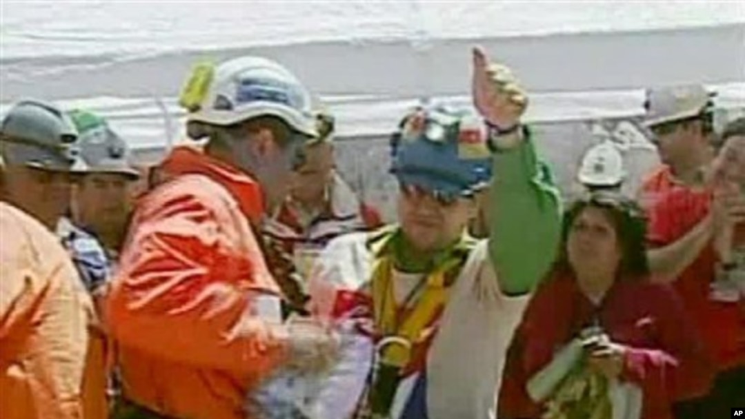 Esteban Rojas, center, the 18th miner to be rescued from the San Jose Mine near Copiapo, Chile, waves after his rescue, 13 Oct 2010