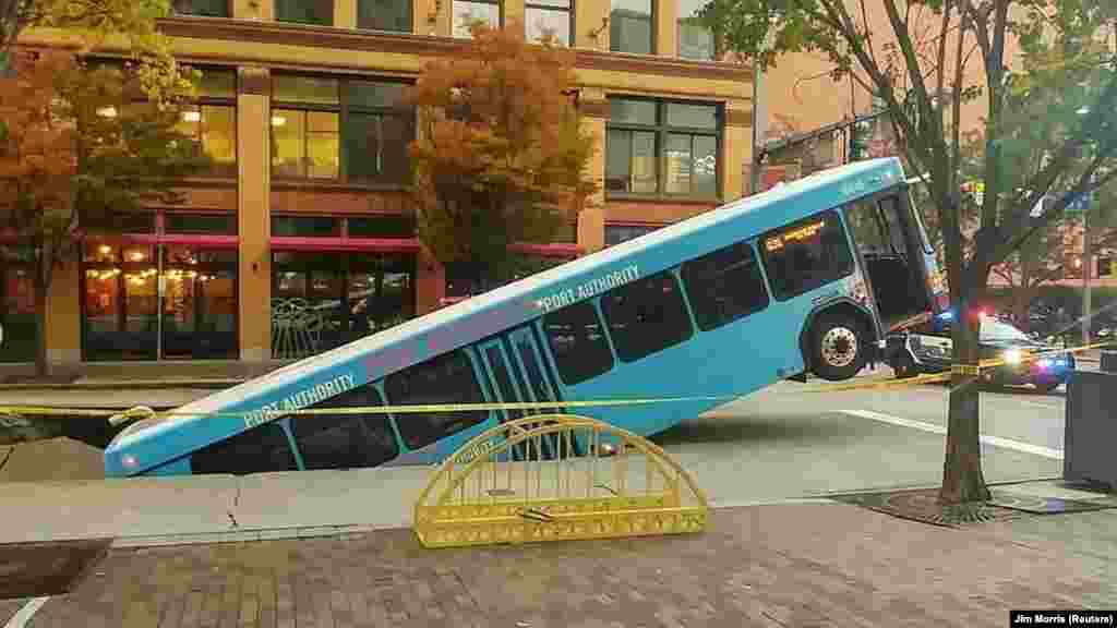 Front of a public bus sticks out of a sinkhole on 10th and Penn Avenue in Pittsburgh, Pennsylvania, in this picture obtained from social media.