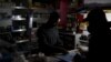 A shopkeeper counts change by the light of a battery-powered lamp during a load-shedding electricity blackout in Cape Town, South Africa, April 15, 2015.