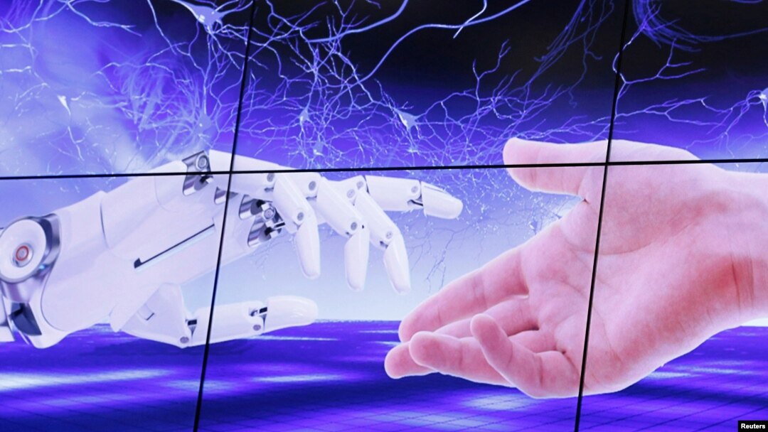 FILE PHOTO: An illustration projected on a screen shows a robot hand and a human one moving towards each others during the "AI for Good" Global Summit at the ITU in Geneva