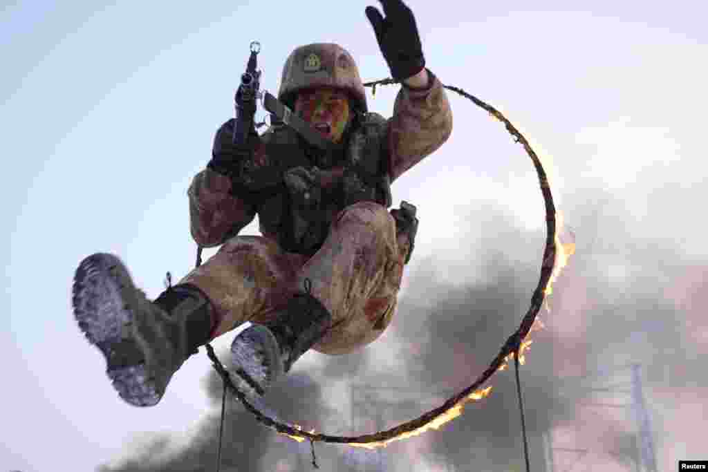 A soldier from the Chinese People's Liberation Army (PLA) jumps through a ring of fire during a military exercise in Shihezi, Xinjiang Uighur Autonomous Region, Dec. 3, 2019.