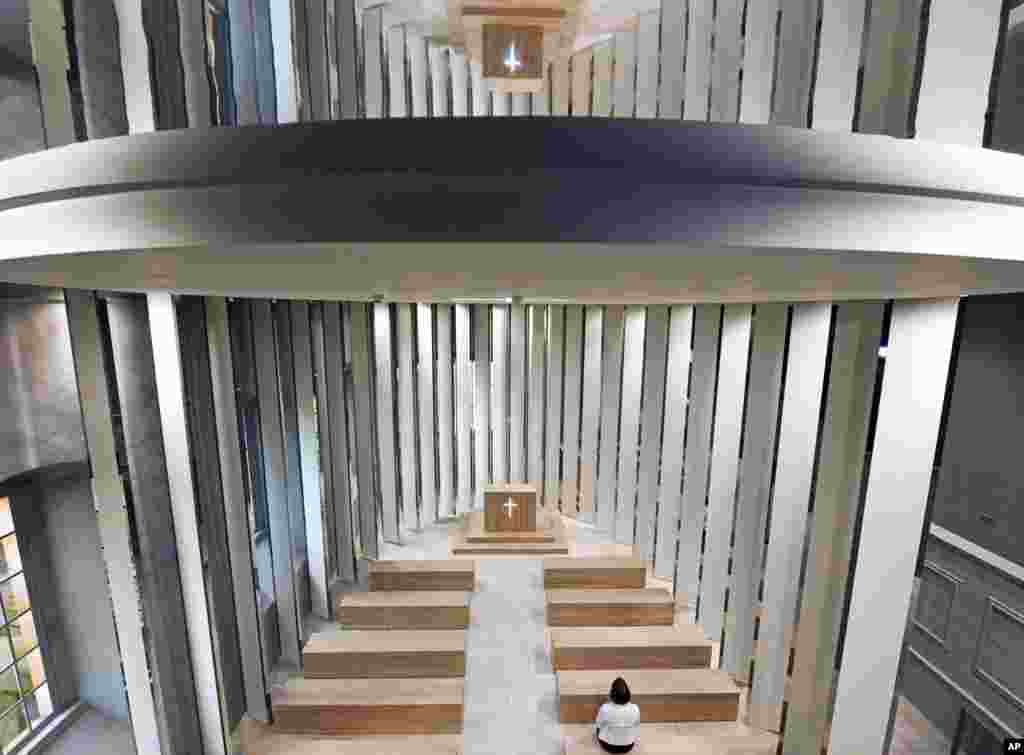 A woman sits on a bench during a press preview of the first porcelain church in Thuringia on Castle Leuchtenburg in Seitenroda, central Germany. Thirty lamellas surrounding the church are made of technical porcelain.