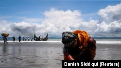 An exhausted Rohingya refugee woman touches the shore after crossing the Bangladesh-Myanmar border by boat through the Bay of Bengal, in Shah Porir Dwip, Bangladesh, on September 11, 2017. (Danish Siddiqui/Reuters)