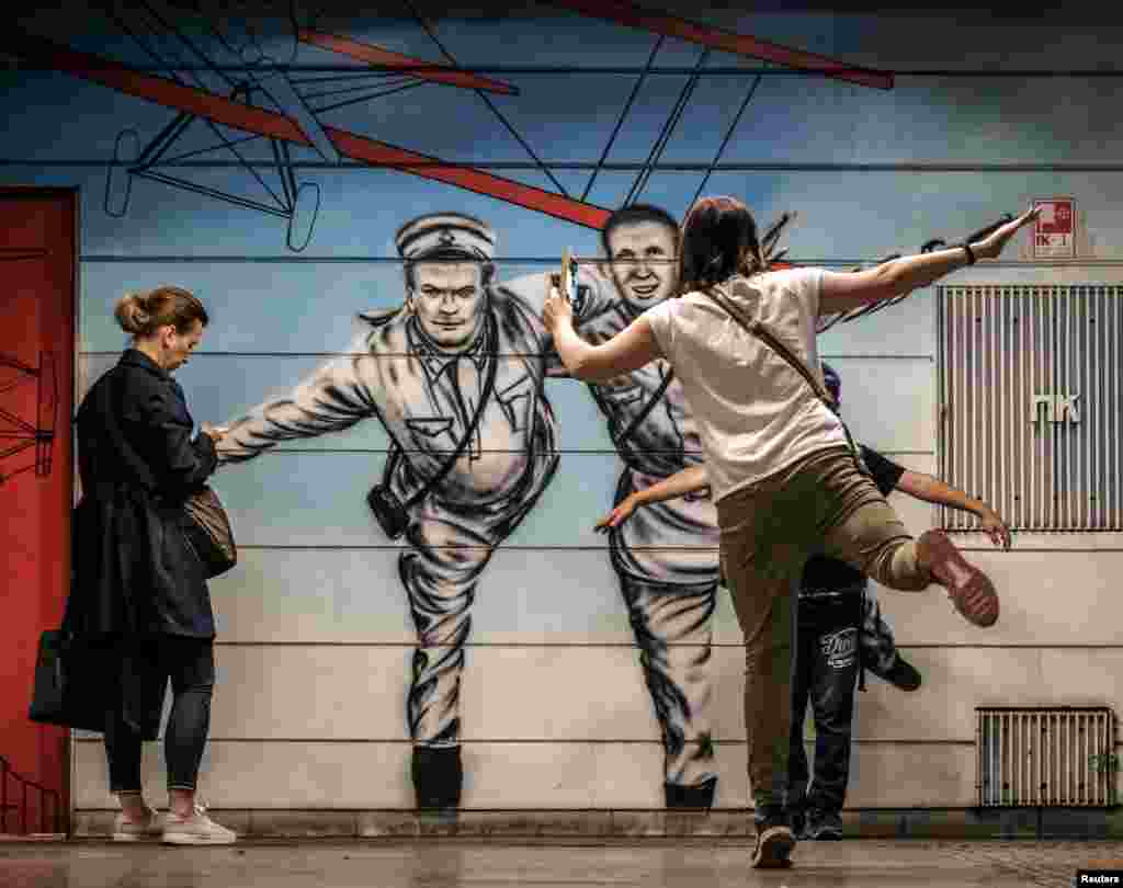 A woman and a boy pose for pictures at Chkalovskaya metro station in Moscow, Russia, in front of a mural depicting Soviet pilot Valery Chkalov - who took a non-stop flight over the Arctic and landed in the U.S. state of Washington in 1937.