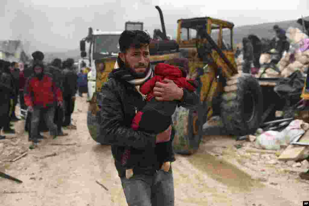 A man carries the body of an earthquake victim in the Besnia village near the Turkish border, Idlib province, Syria, Feb. 6, 2023. 