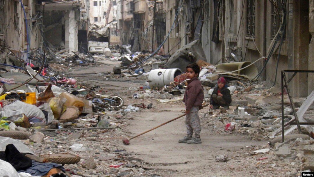 A child clears damage and debris in the besieged area of Homs, Syria, Jan. 26, 2014.