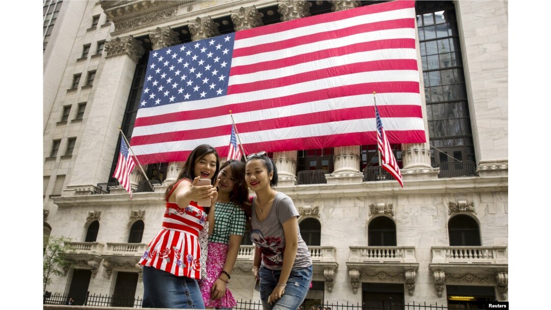 FILE - Chinese tourists take a selfie outside of the New York Stock Exchange, in New York, July 8, 2015.