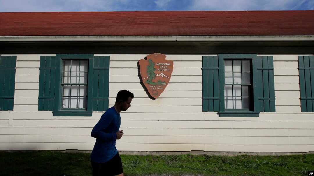 A man runs past a National Park Service sign in San Francisco, Dec. 22, 2018. A partial federal shutdown has been put in motion because of gridlock in Congress over funding for President Donald Trump's Mexican border wall. 