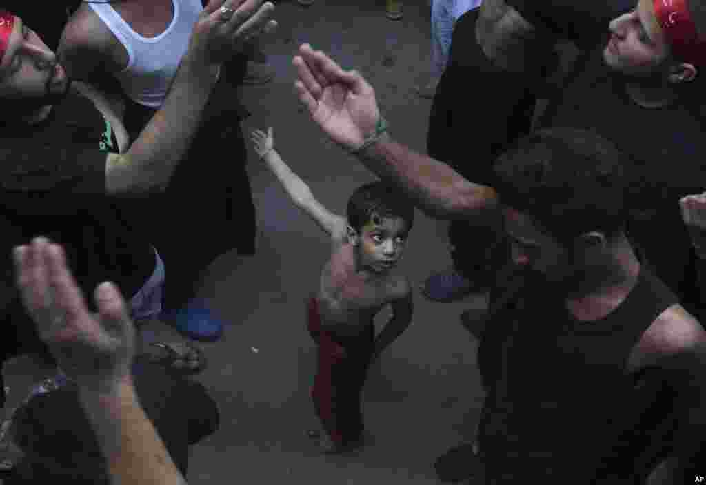 A Shi'ite Muslim child beats his chest next to his father during a procession to mark the end of the 40-day mourning period following the anniversary of the 7th century death of Imam Hussein, the Prophet Muhammad's grandson and one of Shiite Islam's most beloved saints, in Lahore, Pakistan.
