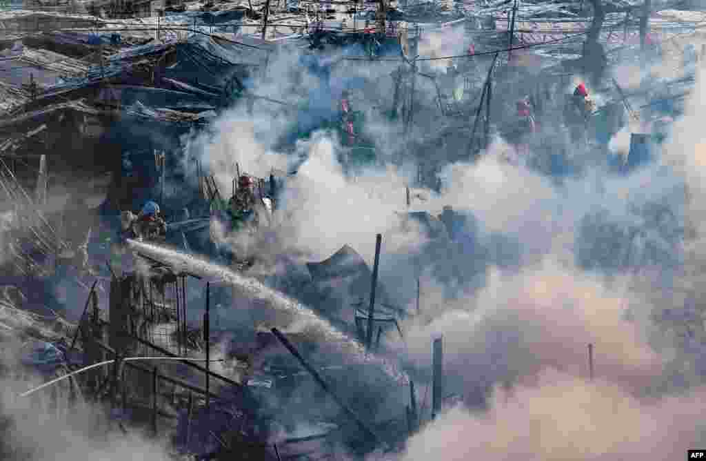Firefighters try to extinguish a fire at the Guryong village, one of South Korea's last remaining slums, in southern Seoul.