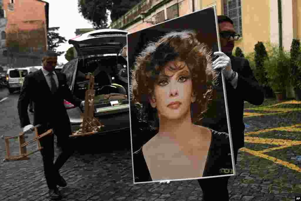 A funeral service employee carries a photo of late Italian film legend Gina Lollobrigida before her laying in state at Rome's Capitol Hill. Lollobrigida, who achieved international stardom during the 1950s and was dubbed "the most beautiful woman in the world" after the title of one of her movies, died in Rome on Jan. 16, 2023. She was 95.