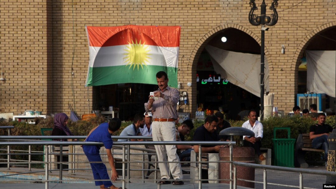 FILE - A man takes a photo of his son near the castle market of Erbil, Iraq, Aug. 17, 2017. 
