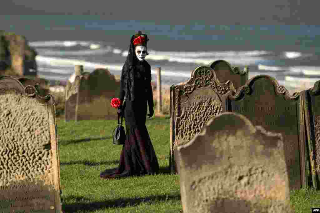 A participant in costume walks between the gravestones in St. Mary's church graveyard during the biannual 'Whitby Goth Weekend' festival in Whitby, northern England.