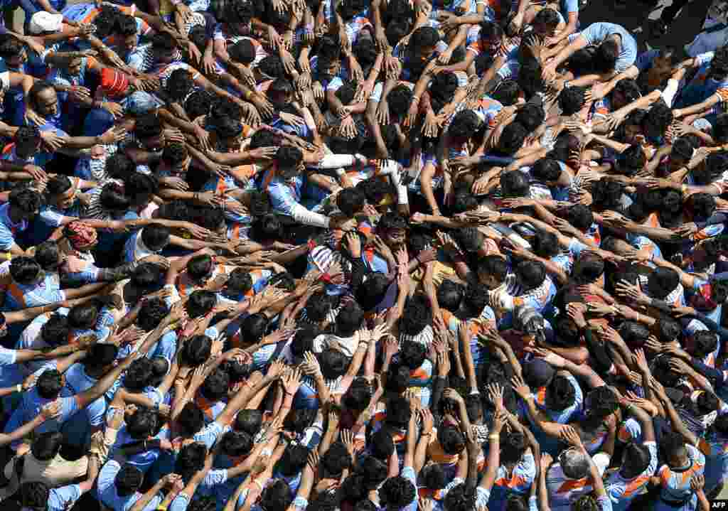 Hindu devotees take a vow before forming a human pyramid in a bid to reach and break a dahi-handi (curd-pot) suspended in the air during celebrations for the 'Janmashtami' festival, which marks the birth of Hindu God Lord Krishna, in Mumbai, India, Aug. 24, 2019.