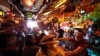 FILE - Patrons enjoy cold tropical cocktails in the tiny interior of the Tiki-Ti bar as it reopens on Sunset Boulevard in Los Angeles.