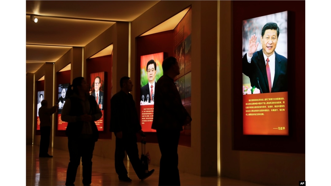 Visitors walk past images of China's past and present leaders, from left, Mao Zedong, Deng Xiaoping, Jiang Zemin, Hu Jintao and Xi Jinping on display at an exhibition on the Long March at the military museum in Beijing, Oct. 24, 2016.