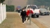 Dos mujeres se alejan de un área en la que los bomberos combaten un incendio forestal en el área de Carolina Forest, al oeste de la ciudad costera de Myrtle Beach, Carolina del Sur, el domingo 2 de marzo de 2025, donde se ordenó que los habitantes evacuaran varios vecindarios. AP