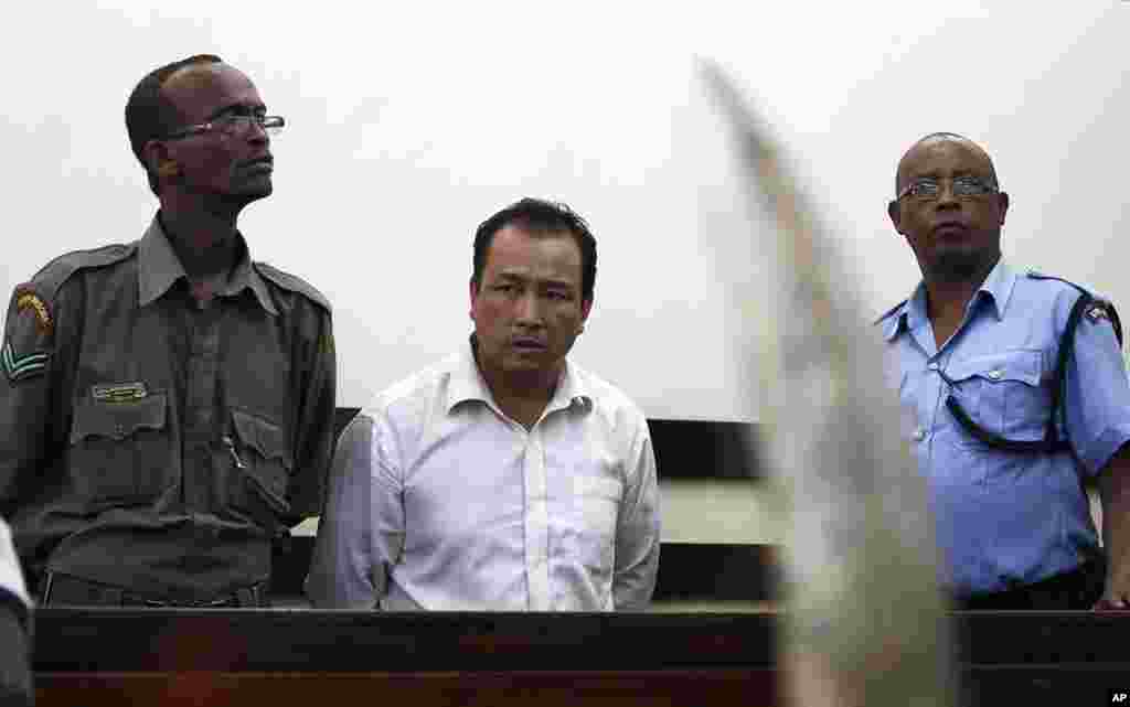 Kenya security stand guard over Tang Yong Jian, a Chinese national who pleaded guilty in the dock of the Makadara Law courts in Kenya's capital, Nairobi, January 28, 2014. Tang, 40, was arrested at the Jomo Kenyatta International airport in Nairobi trying to smuggle 3.4 kilograms of raw ivory to Giuangzhou, China. His punishment was $233,000 or seven years in prison.