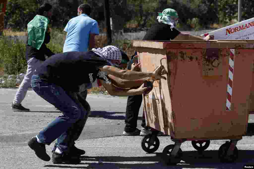 Palestinian protesters take cover during clashes with Israeli troops at a demonstration against the Israeli offensive in Gaza, near the Israeli settlement of Bet El, near Ramallah, West Bank, July 25, 2014. 