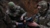 Two soldiers with the 58th Independent Motorized Infantry Brigade of the Ukrainian Army arm a drone with a modified grenade to test it near Bakhmut, Ukraine, on November 25, 2022. (Leah Millis/Reuters)
