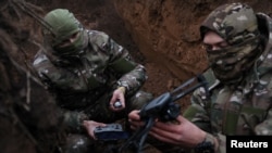 Two soldiers with the 58th Independent Motorized Infantry Brigade of the Ukrainian Army arm a drone with a modified grenade to test it near Bakhmut, Ukraine, on November 25, 2022. (Leah Millis/Reuters)
