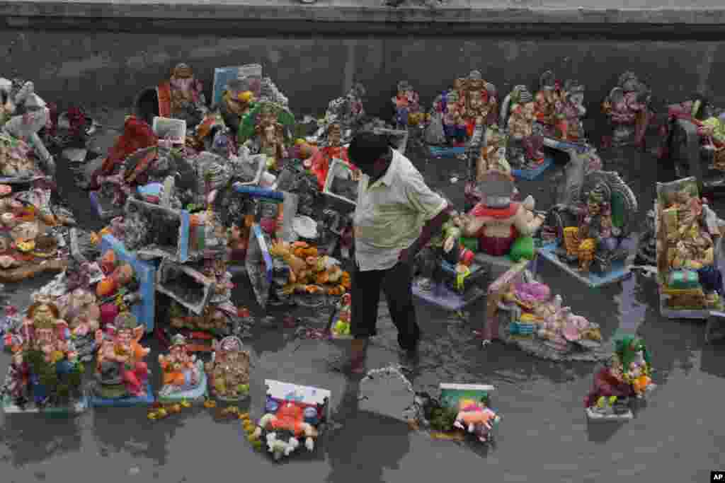 An Indian man forages for reusable items amid idols of Hindu elephant headed god Ganesha and offerings, a day after the immersion of idols, in Ahmadabad, India.
