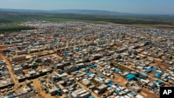 FILE - This April 19, 2020 photo shows a large refugee camp on the Syrian side of the border with Turkey, near the town of Atma, in Idlib province, Syria. 