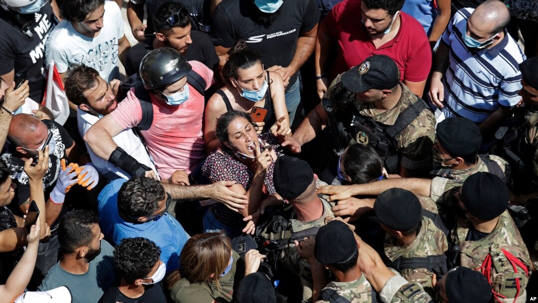 A woman yells at Lebanese soldiers during scuffles with the soldiers who are blocking a road as French President Emmanuel Macron visits the Gemmayzeh neighborhood, which suffered extensive damage from the Tuesday explosion at the seaport, in Beirut.
