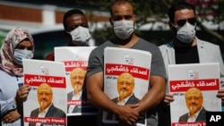 People hold posters of slain Saudi journalist Jamal Khashoggi, near the Saudi Arabia consulate in Istanbul, marking the two-year anniversary of his death, Oct. 2, 2020.