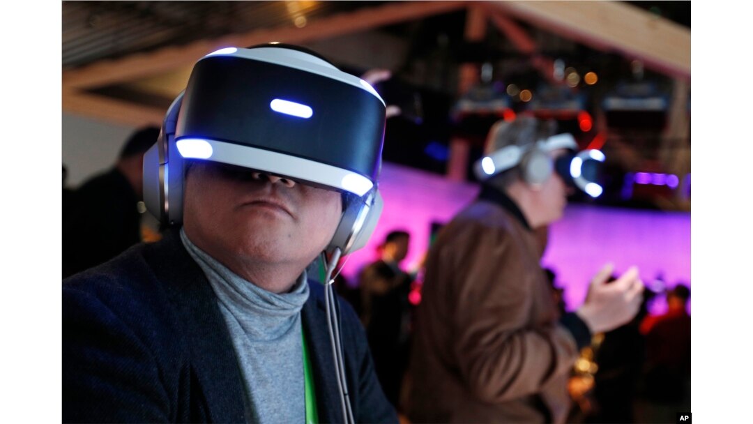 FILE - People look through Sony PlayStation VR headsets after a Sony news conference at CES International in Las Vegas, Jan. 8, 2018.