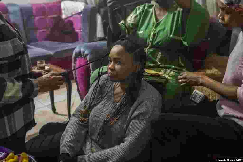 Mona, a Sudanese English teacher, has her hair braided by her fellow displaced countrywomen in Cairo on Dec. 17, 2024. “We leave Sudan, but Sudan does not leave us,” she said.