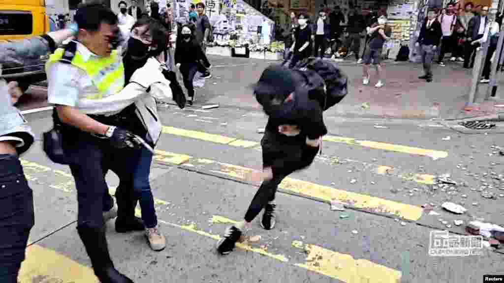 A still image from a social media video shows a protester try to prevent a police officer from aiming his gun at a protester in Sai Wan Ho, Hong Kong.