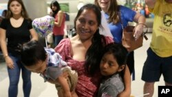 Buena Ventura Martín-Godínez, (centro), sostiene a suh hijo Pedro, (izquierda) cuando se reúne con su hija Janne, (derecha), en el Aeropuerto Internacional de Miami, el domingo 1 de julio de 2018. Martín ingresó ilegalmente a EE.UU. desde México en mayo con su hijo huyendo de la violencia en Guatemala. Su esposo cruzó dos semanas después con Janne. Todos fueron capturados por la patrulla fronteriza y separados. La niña fue liberada el domingo de una agencia de bienestar infantil en Michigan. (AP Photo/Lynne Sladky)