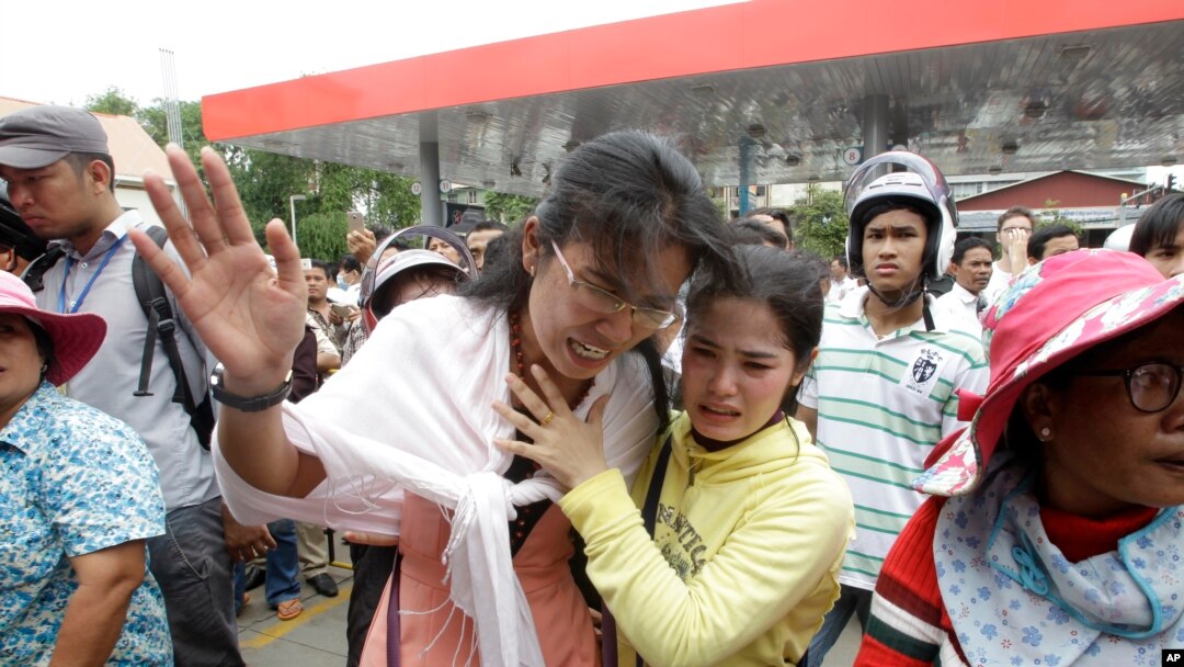 Cambodians cry outside a shopping mall where prominent political analyst Kem Ley was shot dead in Phnom Penh, Cambodia, Sunday, July 10, 2016.