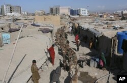 FILE - Afghan boy shepherds walk their sheep near temporary housing in Kabul, Afghanistan, May 30, 2016.