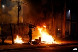 A protester carries a chair to a fire outside the Congress building during clashes between police and protesters opposing a constitutional amendment that would allow the election of a president to a second term, in Asuncion, Paraguay, March 31, 2017.