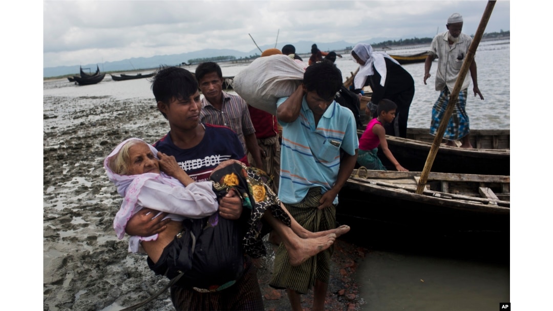 A Rohingya ethnic minority from Myanmar carries an elderly woman as they alight from a local boat on which they crossed a river, after crossing over to the Bangladesh side of the border near Cox's Bazar's Dakhinpara area, Sept. 2, 2017.