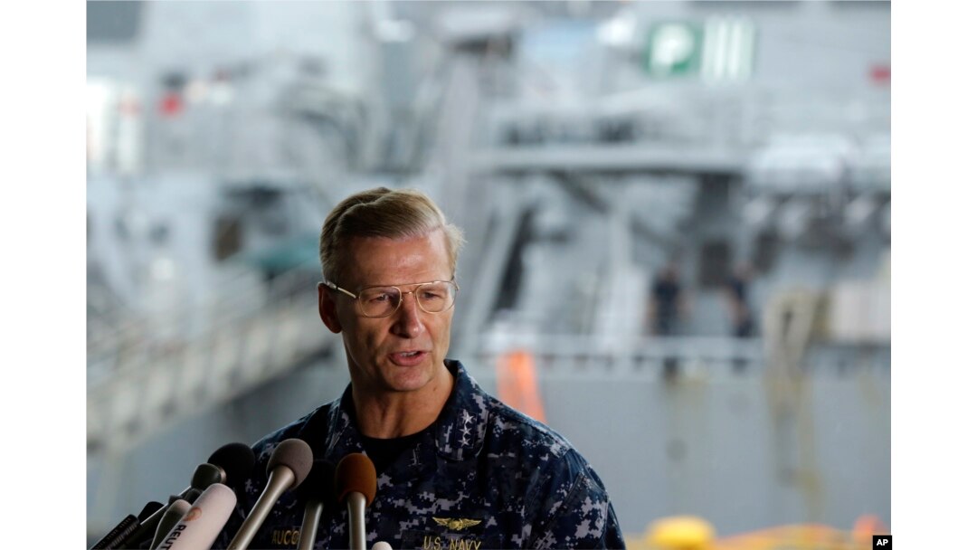 Vice Adm. Joseph Aucoin, commander of the U.S. 7th Fleet, speaks during a press conference, with the damaged USS Fitzgerald in the background at the U.S. Naval base in Yokosuka, southwest of Tokyo, June 18, 2017.